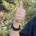 Load image into Gallery viewer, Viking Collection - Real Shungite Bracelet with Cross, 10mm bead - on a model giving a thumbs up, wearing 2 Shungite bracelets, sold separately - BellaChel Jeweler
